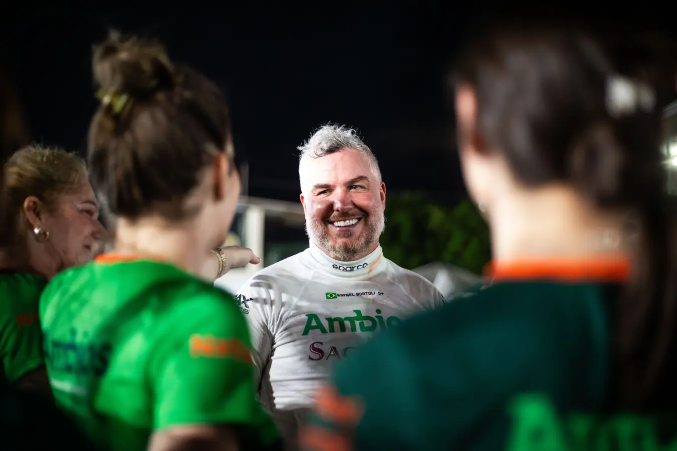 Rafael sorrindo à noite cercado de pessoas de camiseta verde